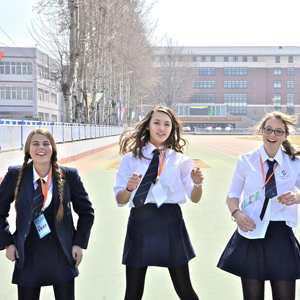 Three girls outdoors in a city wearing formal school uniform