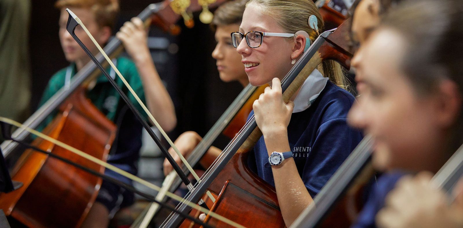 Female and male students playing cello in school orchestra