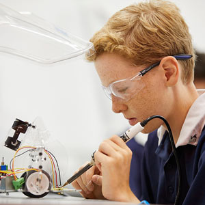 Closeup of male student wearing safety glasses and using a soldering iron