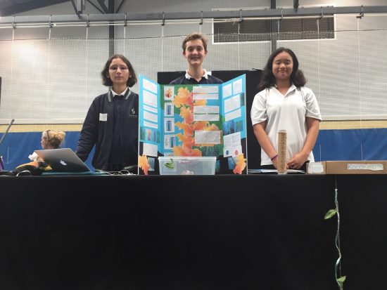 Three students with a presentation of early tsunami warning system smiling