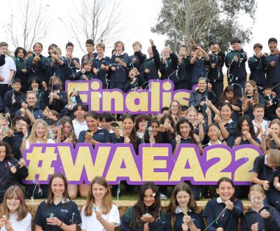a large group of students let off streamers in celebration alongside large text signs that read 'Finalist' and '#WAEA22'