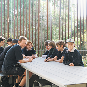 A group of students sitting around an outside table chatting.